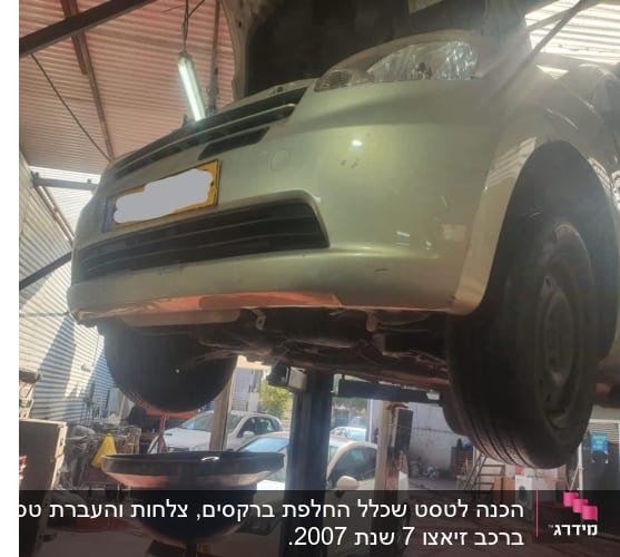 רכב מורם על ליפט במוסך עם כלי איסוף שמן